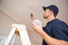 A worker installing a smoke detector.