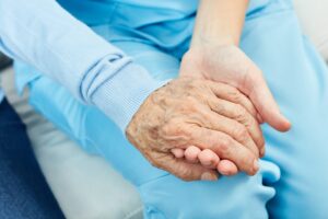 Elderly person's hand being held by a young woman
